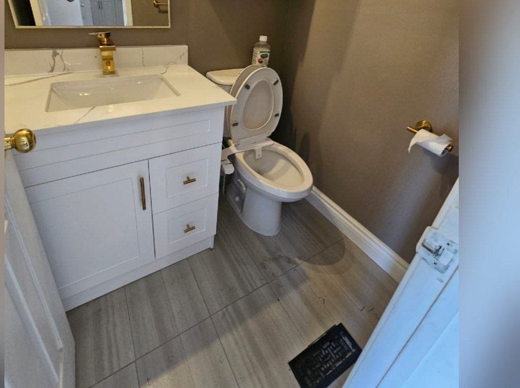After: renovated powder room with white vanity, gold faucet, quartz counter and tiled floor
